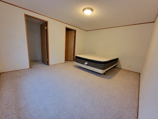 An empty bedroom with a bed and a closet.