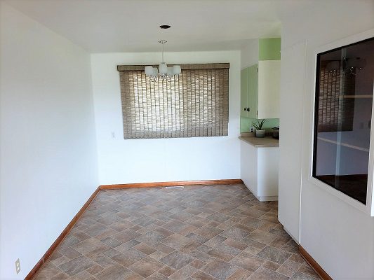 An empty kitchen with tile floors and a window.