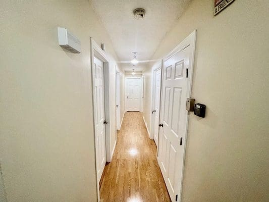 A hallway with white doors and hardwood floors.