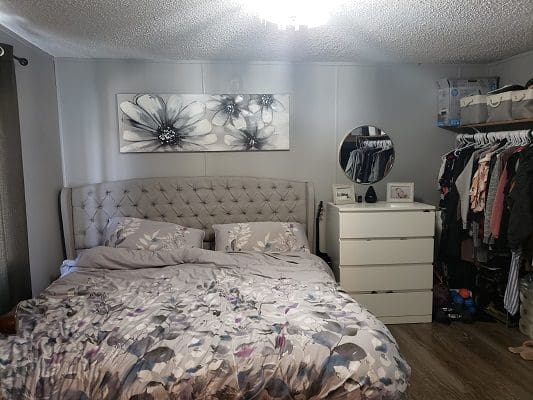 A bedroom with a bed, dresser and closet.
