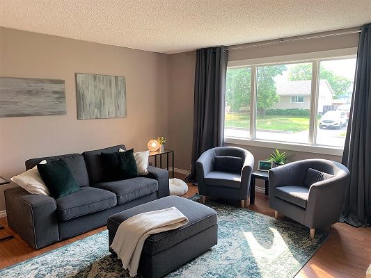 A living room with grey furniture and a window.