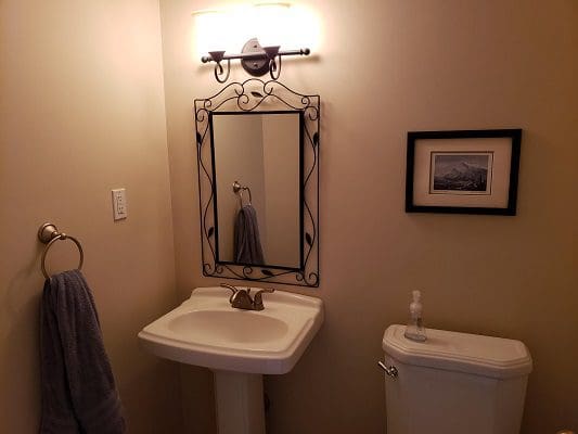 A bathroom with a toilet, sink and mirror.