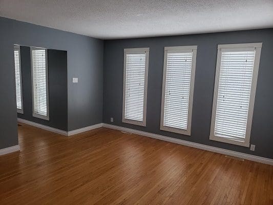 Empty living room with hardwood floors and shutters.