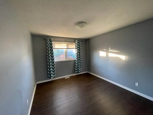 An empty room with blue walls and hardwood floors.