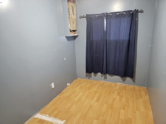 An empty room with blue curtains and wood floors.