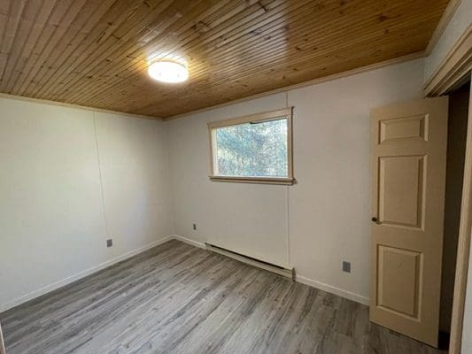 An empty room with wood floors and a window.