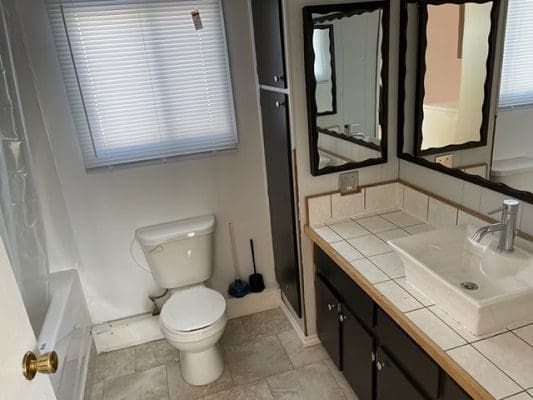 A bathroom with a sink, toilet and mirror.