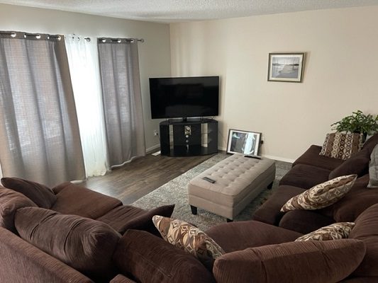 A living room with brown couches and a tv.