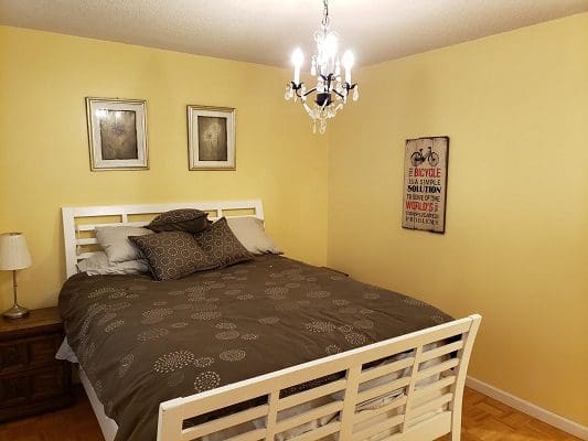 A bed in a bedroom with yellow walls and a chandelier.