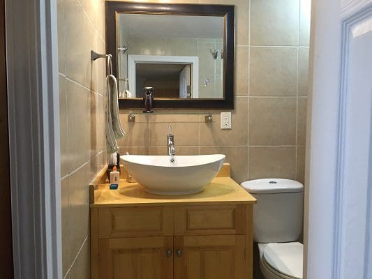 A bathroom with a sink, toilet and mirror.