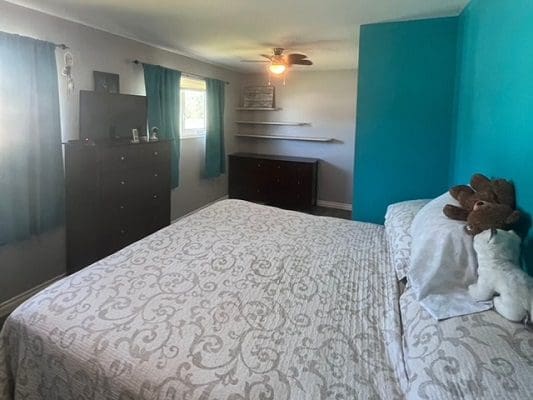 A bedroom with blue walls and a stuffed teddy bear.