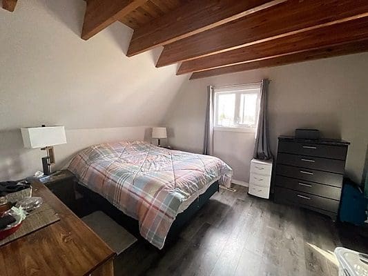 A bedroom with wood floors and a bed.