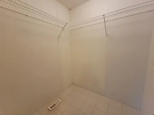 An empty closet with a white tile floor.