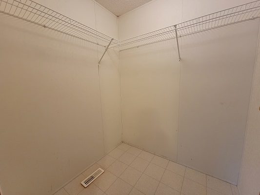 An empty closet with a white tile floor.