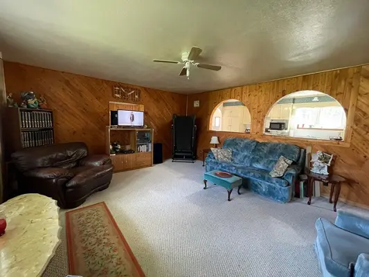 A living room with couches and a ceiling fan.