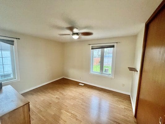 An empty room with hardwood floors and a ceiling fan.