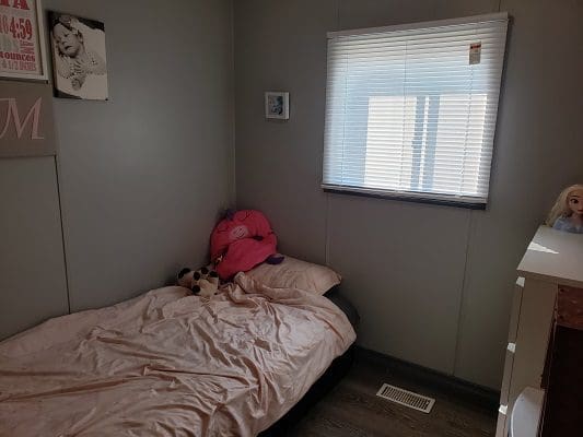 A small bedroom with a bed and a teddy bear.