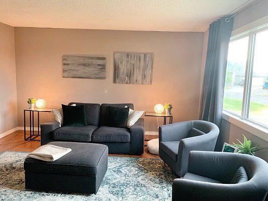 A living room with a couch, chairs and a window.