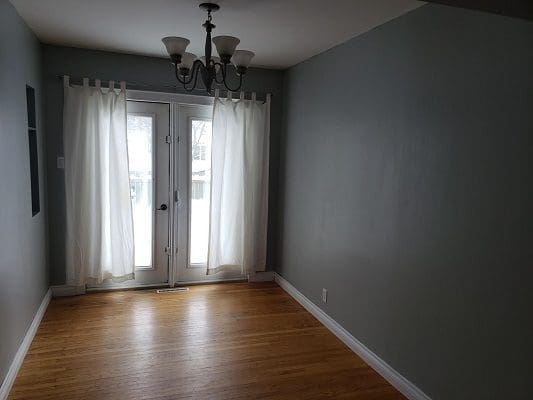 An empty room with gray walls and hardwood floors.