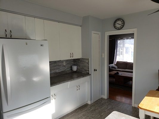 A kitchen with white cabinets and a ceiling fan.