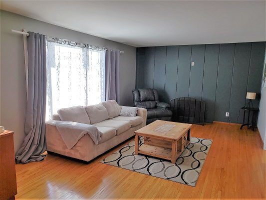 A living room with gray walls and hardwood floors.