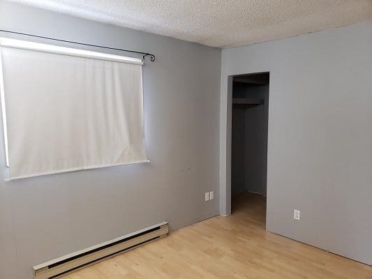 An empty room with wood floors and a window.
