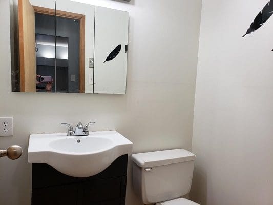 A bathroom with a toilet, sink and mirror.