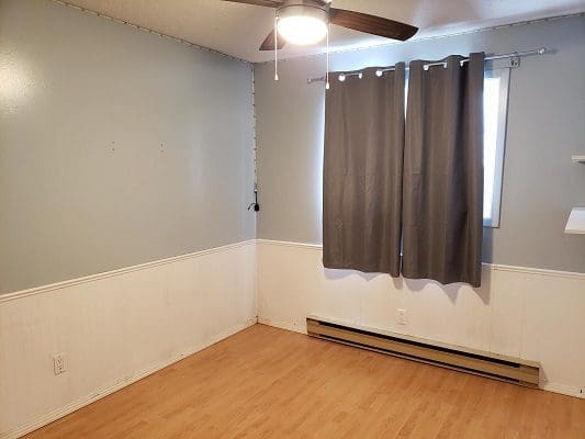 An empty room with wood floors and a ceiling fan.