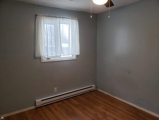 An empty room with wood floors and a ceiling fan.