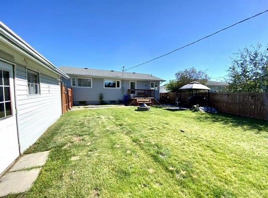 The backyard of a house with grass and a lawn mower.