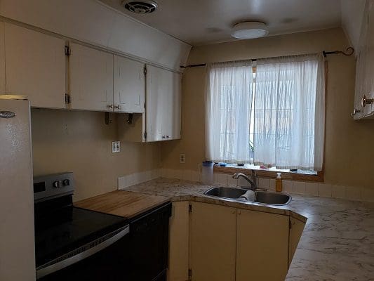 A kitchen with white cabinets and a sink.