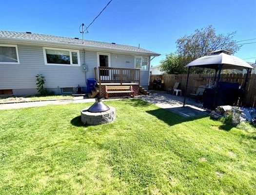 A backyard with grass and a fire pit.