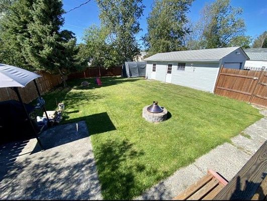 A backyard with grass and a fire pit.