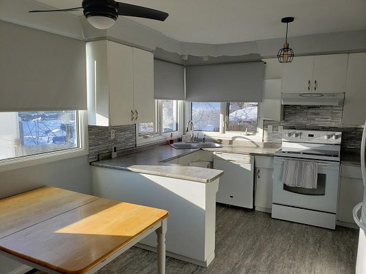 A kitchen with white cabinets and a table and chairs.