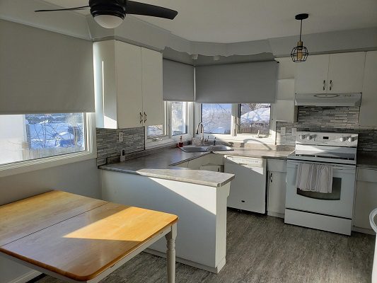 A kitchen with white appliances and a table.