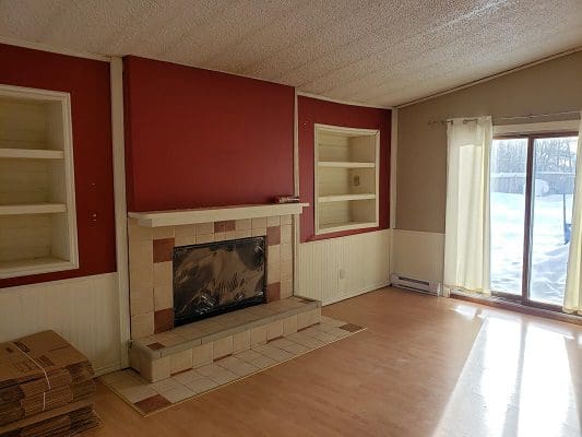 An empty living room with red walls and a fireplace.