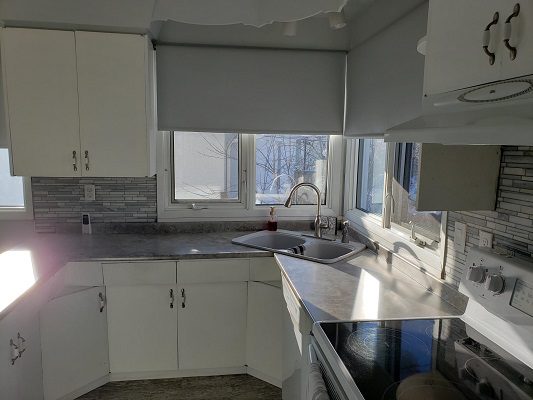 A kitchen with white cabinets and a sink.