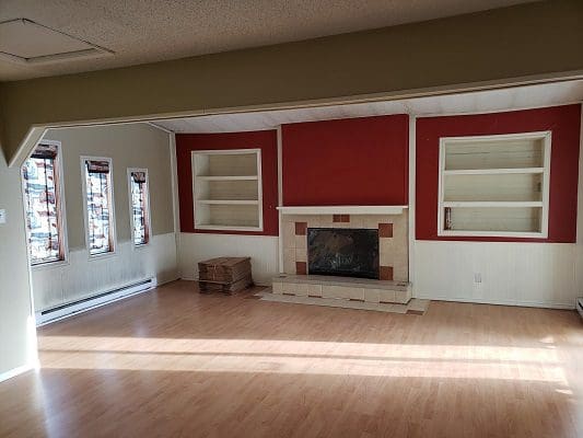 An empty living room with red walls and a fireplace.