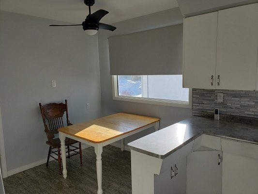 A kitchen with a table and chairs and a ceiling fan.