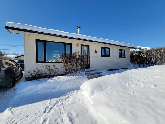 A house with snow on the ground and a car parked in front of it.