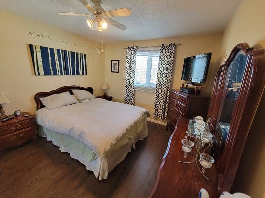 A bedroom with hardwood floors and a ceiling fan.