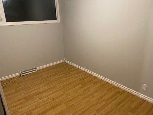 An empty room with hardwood floors and a window.