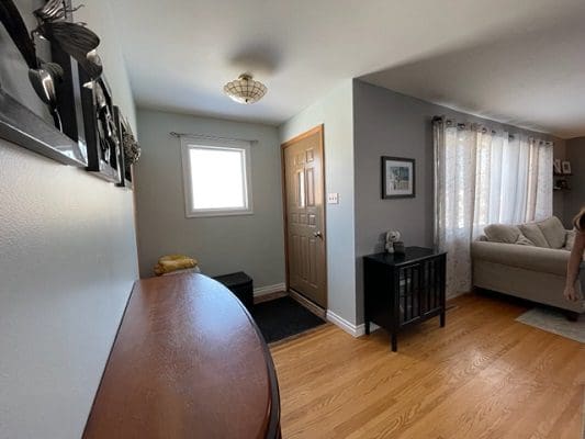 A woman is standing in a living room with hardwood floors.