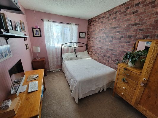 A bedroom with pink walls and a brick wall.