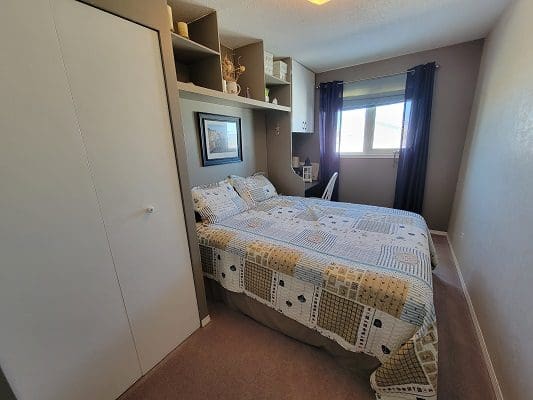A bedroom with a bed, dresser and closet.