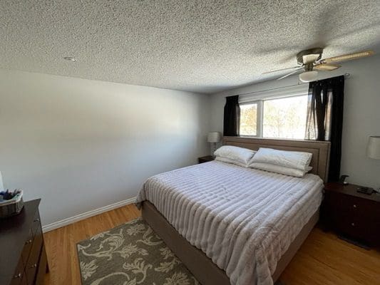 A bedroom with hardwood floors and a ceiling fan.