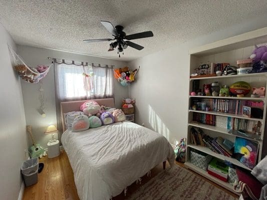 A bedroom with stuffed animals and a ceiling fan.