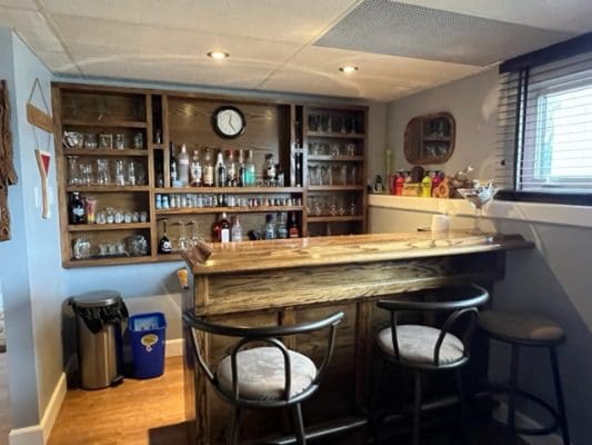A home bar with stools and a bottle of liquor.