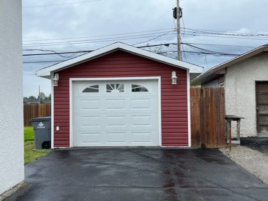 A red and white garage in a backyard.