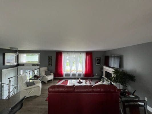 A living room with a red couch and red curtains.